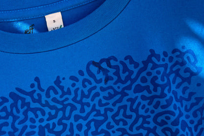 Detailansicht von einem blauen T-Shirt in der Größe S. Das T-Shirt hat einen welligen Druck auf der Brust.