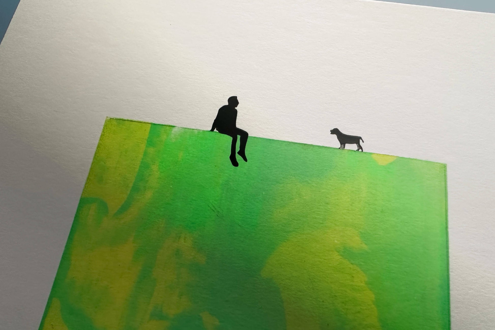 Detail Siebdruck Gruen gelb MILO auf Passpartoutverschnitt 20x26,5cm zu sehen auf blauer Wand
