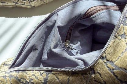 Close up einer geöffneten Umhängetasche mit einem beigen Muster. Der Hintergrund ist weiß