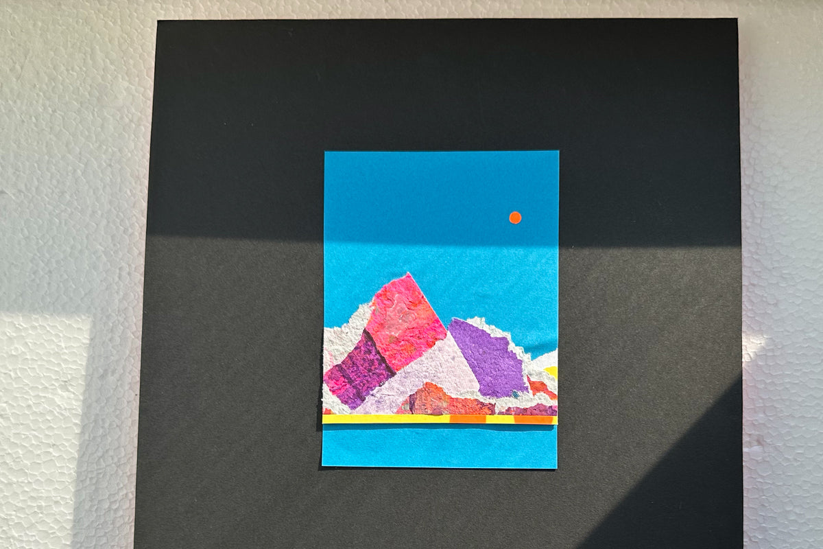 Collage von vorne zeigt eine abstrakte, pink-violette Bergkulisse auf blauen Hintergrund, umrahmt von einem schwarzen, großen Passepartout. jeff-everyPieceAFriend