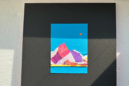 Collage von vorne zeigt eine abstrakte, pink-violette Bergkulisse auf blauen Hintergrund, umrahmt von einem schwarzen, großen Passepartout. jeff-everyPieceAFriend