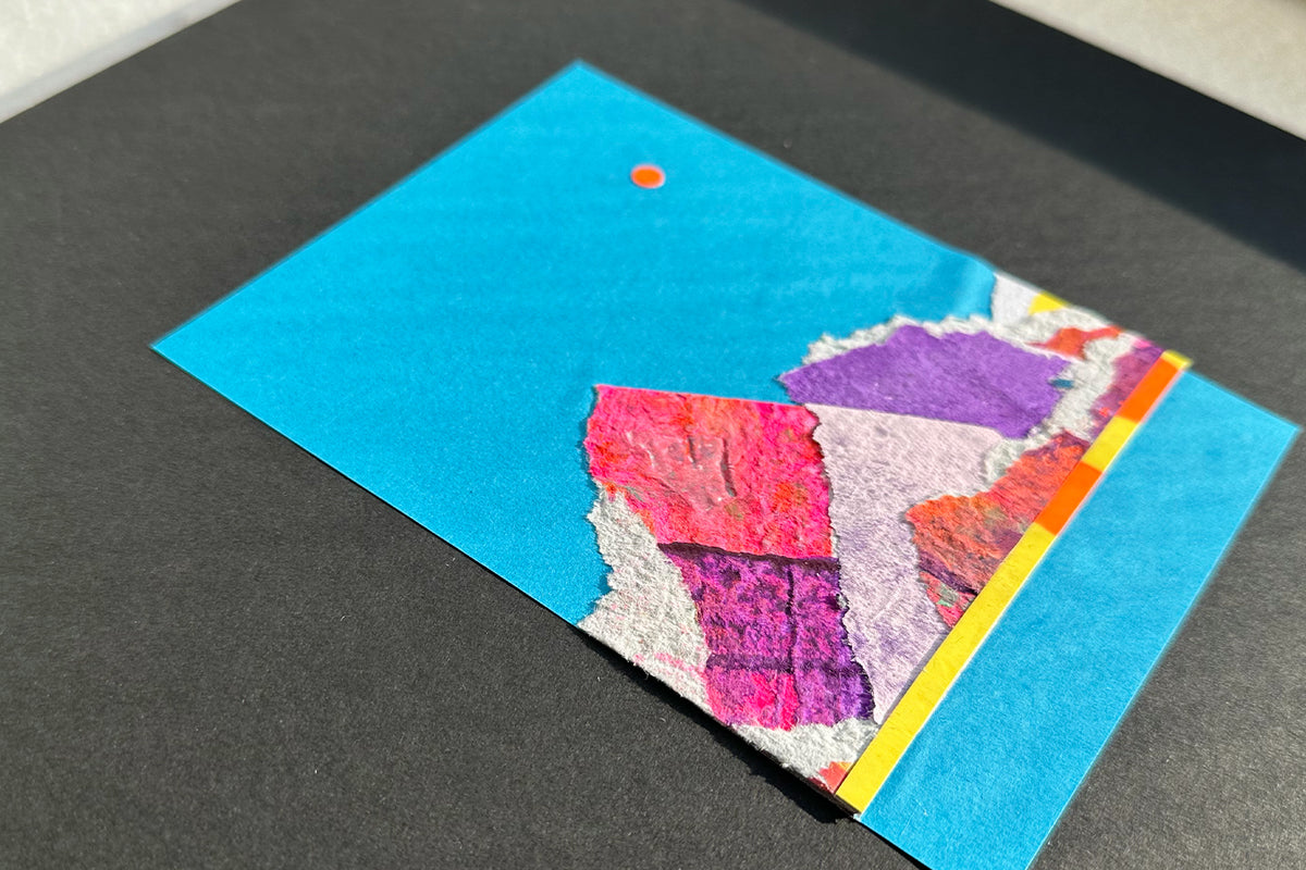 Collage von schräg oben zeigt eine abstrakte, pink-violette Bergkulisse auf blauen Hintergrund, umrahmt von einem schwarzen, großen Passepartout. jeff-everyPieceAFriend
