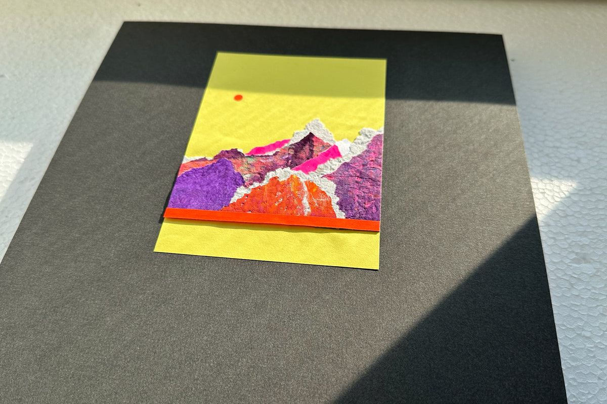 Collage von schräg vorne zeigt eine abstrakte, pink-violette Bergkulisse auf gelben Hintergrund, umrahmt von einem schwarzen, großen Passepartout. jeff-everyPieceAFriend