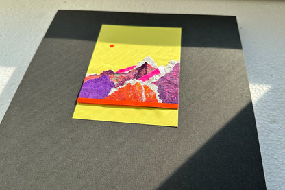 Collage von schräg vorne zeigt eine abstrakte, pink-violette Bergkulisse auf gelben Hintergrund, umrahmt von einem schwarzen, großen Passepartout. jeff-everyPieceAFriend