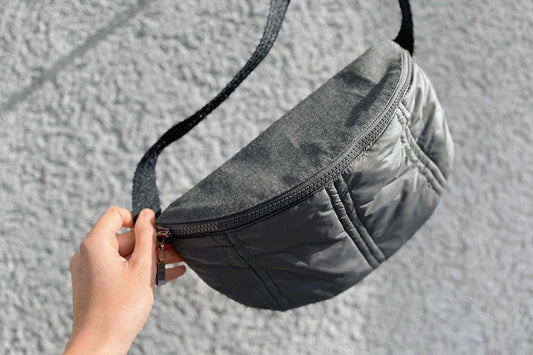 Hand hält Pufferbag aus upgecycelter Jacke ins Bild