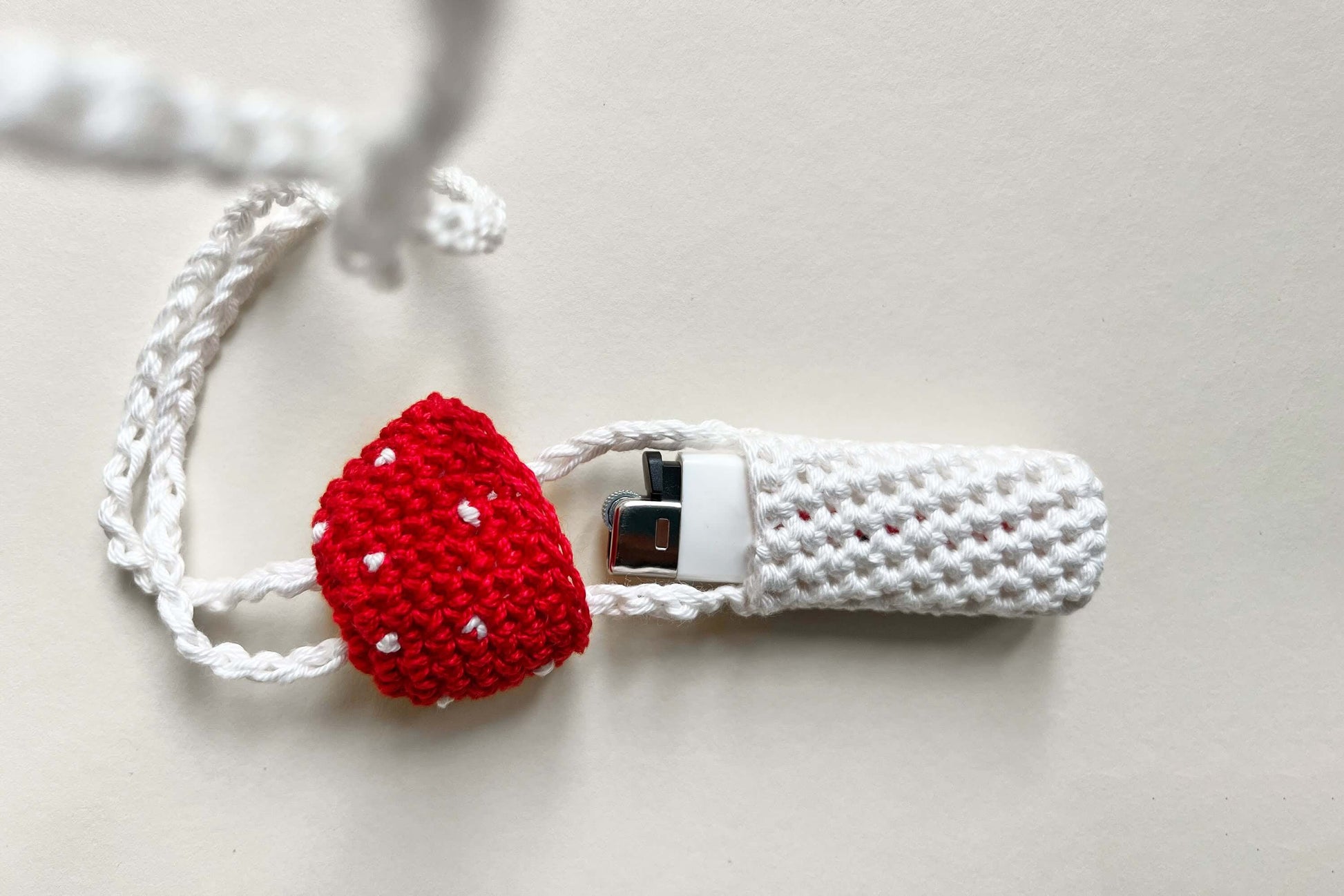 Ein gehäkelter Feuerzeughalter zum Umhängen in rot-weißer Fliegenpilzoptik