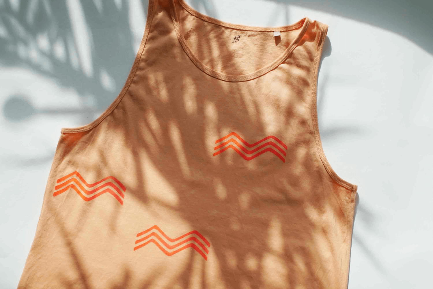 Wellenförmiger Siebdruck mit orange rot Verlauf auf Pfirsich-farbenem Unisex-Tanktop