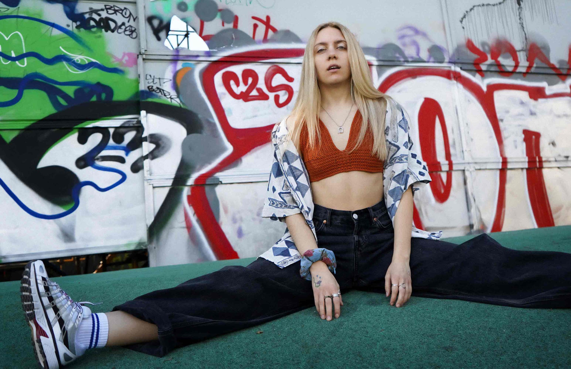 Junge, lässige Frau trägt ein oranges Häkeltop YAEL, aus Wolle aus zweiter Hand gehäkelt und Scrunchie TRULLA aus Upcycling-Jeans von jeff every piece a friend