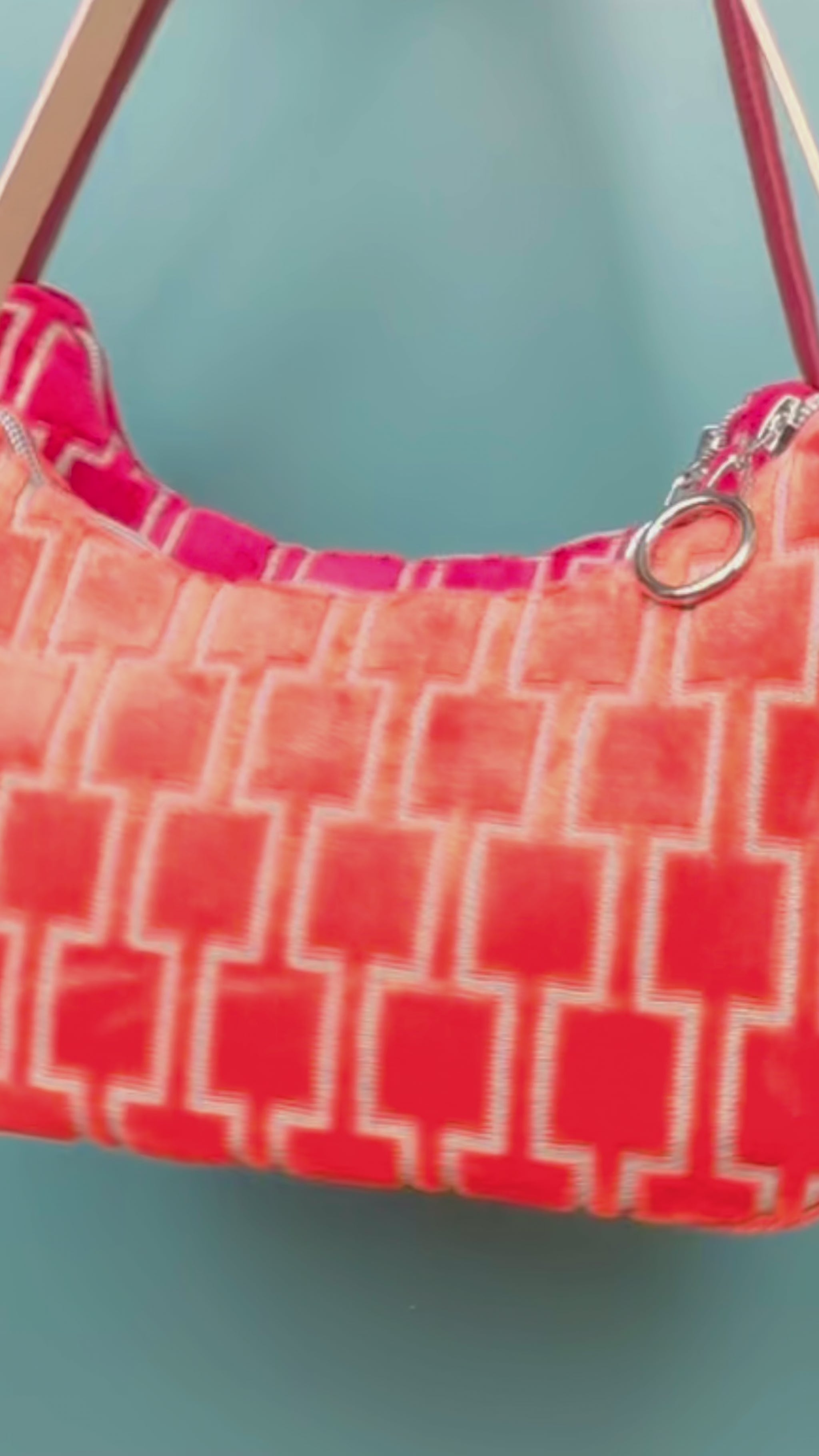 Viedeo Gesamtansicht: Zwei Schultertaschen im Vintagestil vor blauen Hintergrund. Eine Tasche ist orange gemustert, die andere Tasche ist rot gemustert. Beide Taschen wurden von aus upcycled Materialien von Jeff Every Piece A Friend hergestellt.